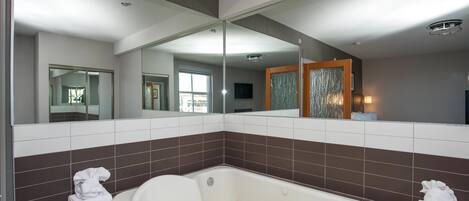 Un baño moderno con una bañera grande, un espejo y piso de baldosas.