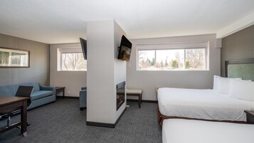 Una habitación de hotel con cama, sofá, escritorio, televisor y dos ventanas.