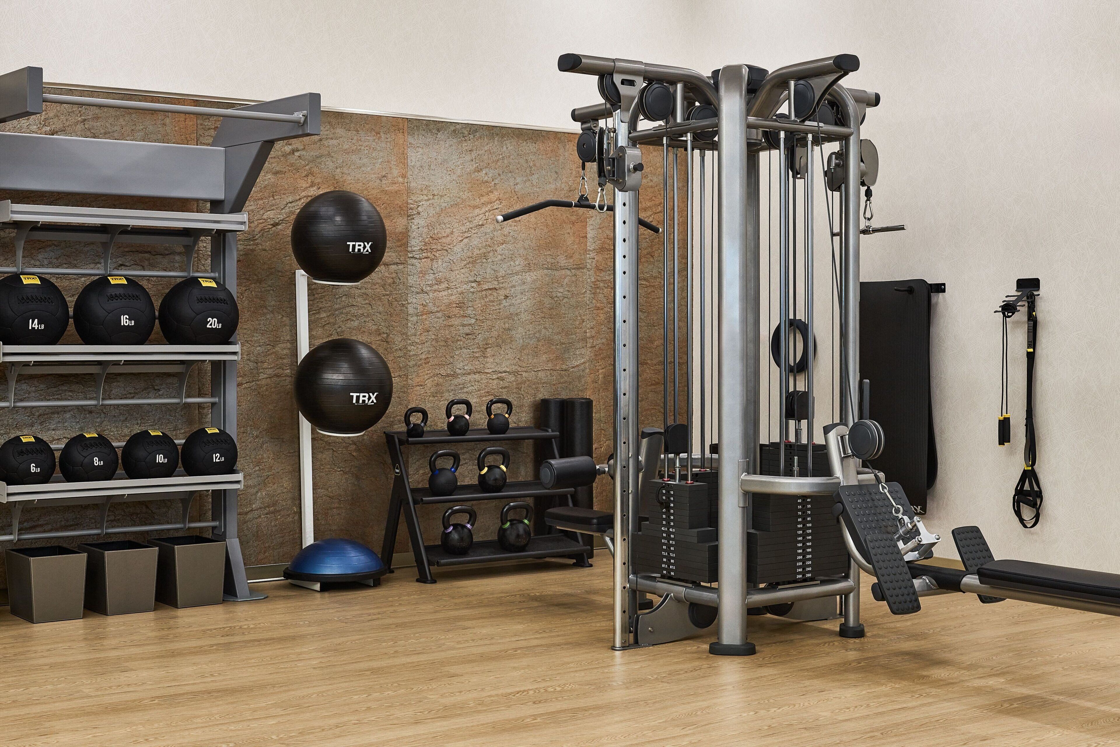 A gym with weightlifting equipment, kettlebells, and exercise balls.