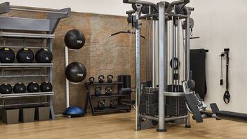 A gym with weightlifting equipment, kettlebells, and exercise balls.