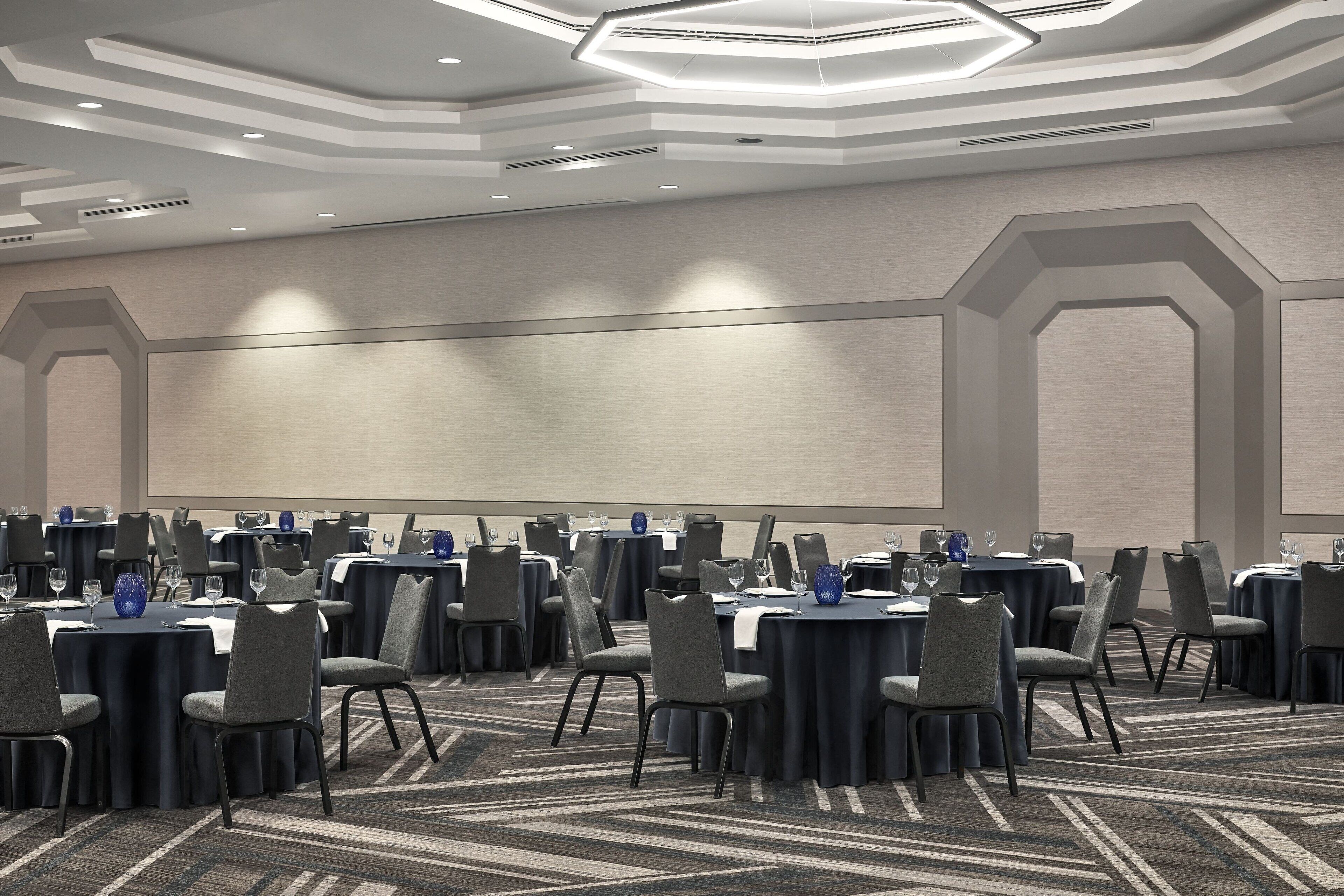 A conference room with round tables, chairs, and a large screen.