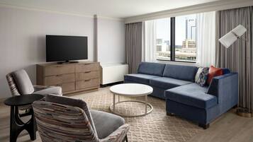 A modern living room with a flat-screen TV, a sofa, a chair, and a coffee table.