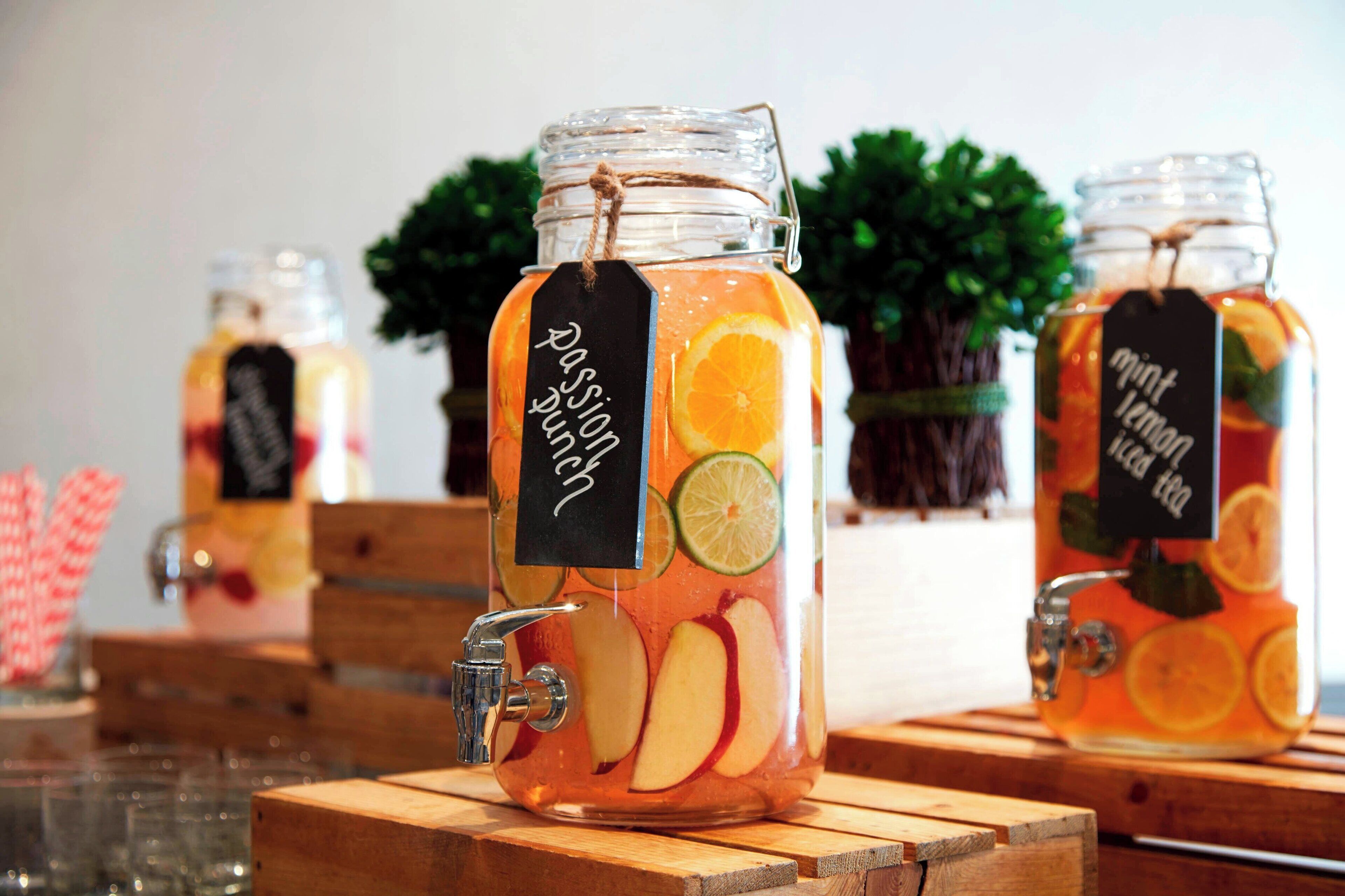 Drie glazen potten met fruitplakjes en etiketten, geplaatst op houten voetstukken.