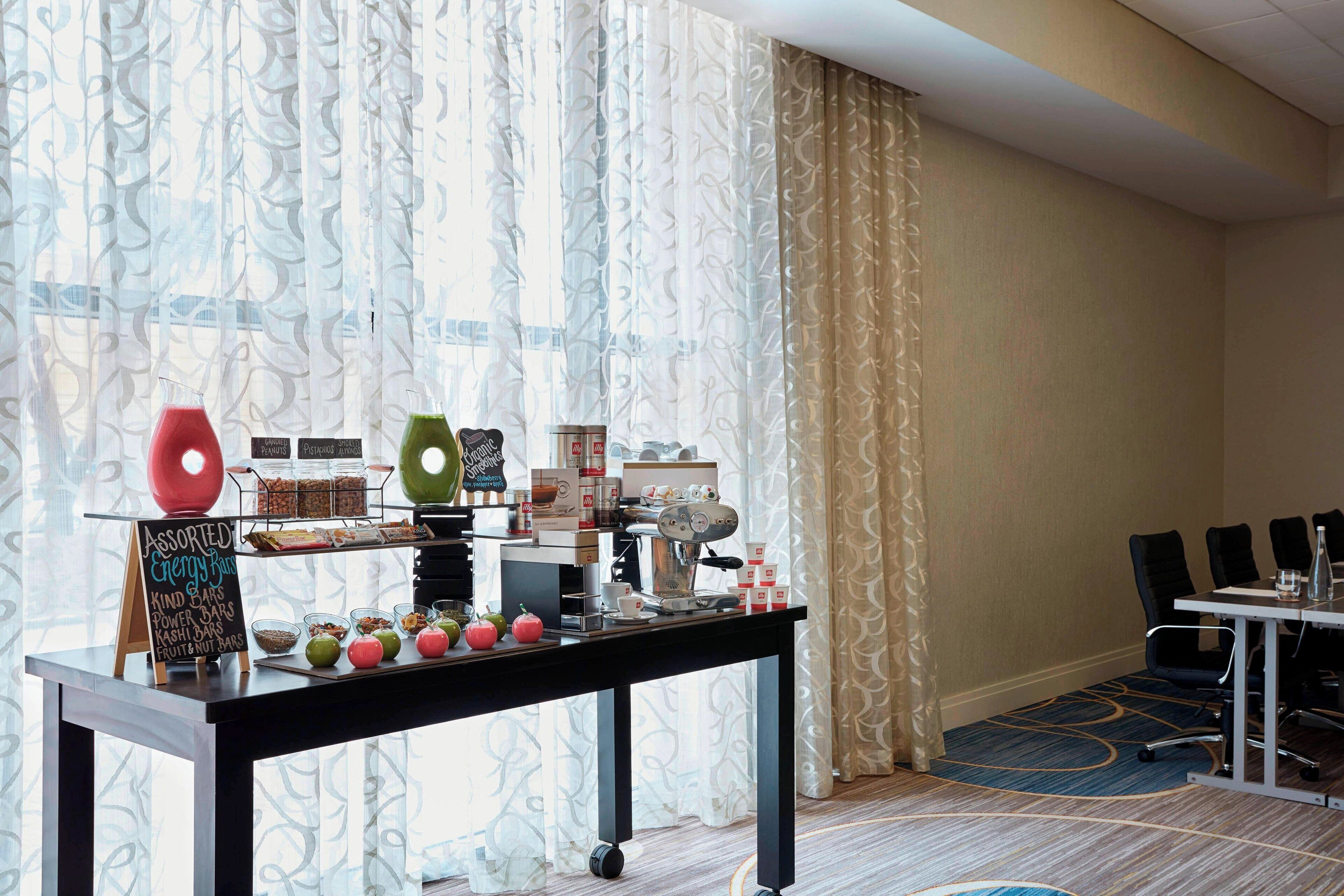 A breakfast buffet setup with assorted items, a coffee machine, and a seating area with chairs and a table.