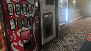 Vending machines with beverage options, a water dispenser, and a patterned carpet. - Economy Inn North Randall (North Randall)