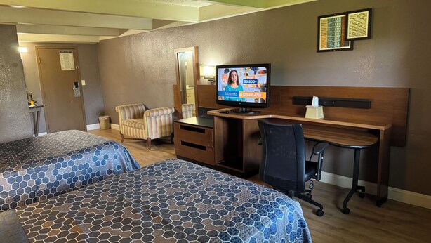 A hotel room with two beds, a desk, a chair, a television, and a mirror. - Economy Inn North Randall (North Randall)