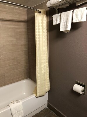 A bathroom with a bathtub, a shower curtain, and a towel rack with multiple towels.