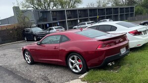 A red sports car parked in a lot with a building in the background. - Economy Inn North Randall (North Randall)