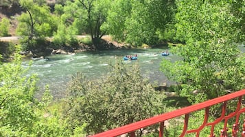 Une rivière où l’on peut faire du rafting, bordée de verdure et d’une rambarde rouge.