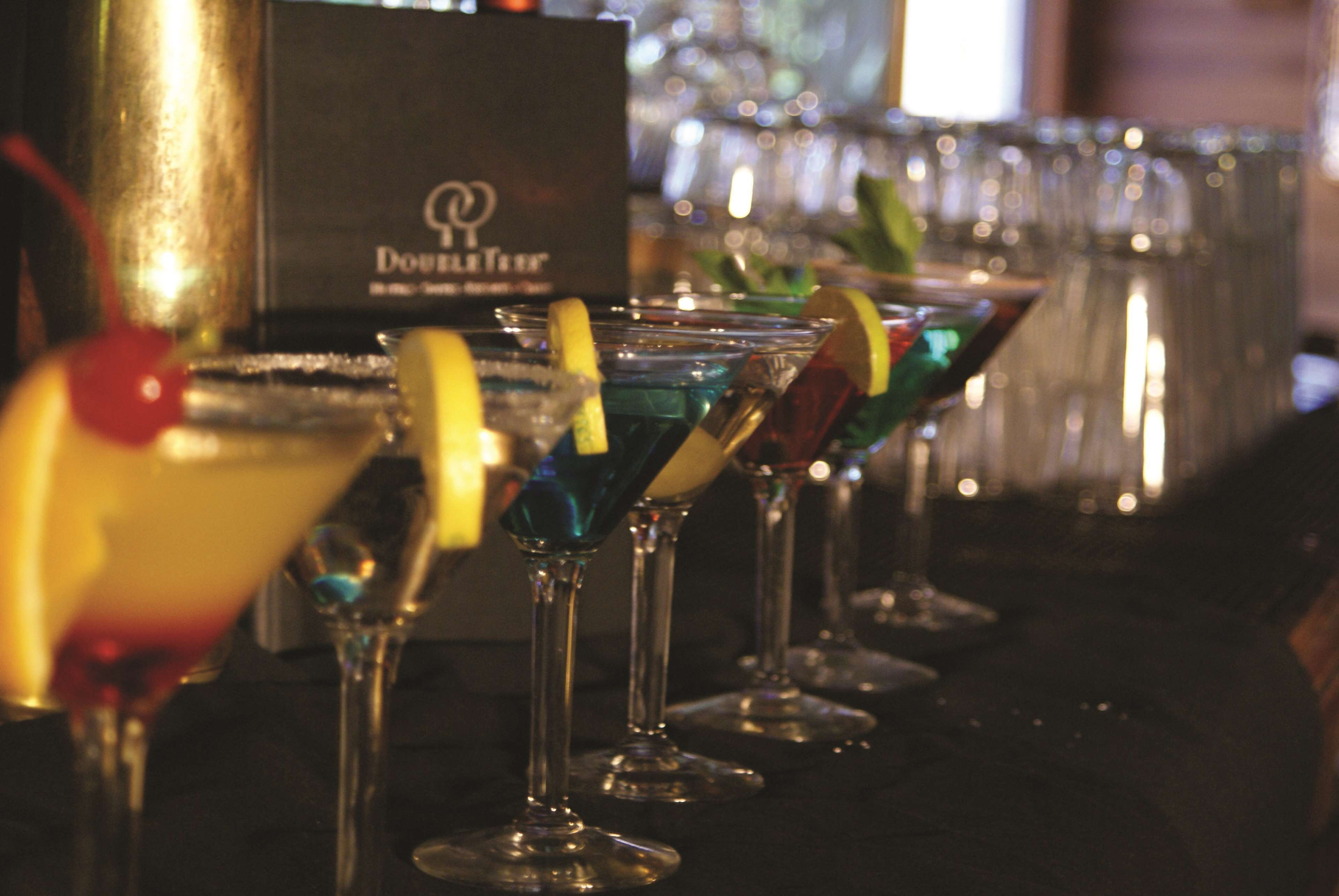 A row of martini glasses with colorful garnishes on a bar counter.