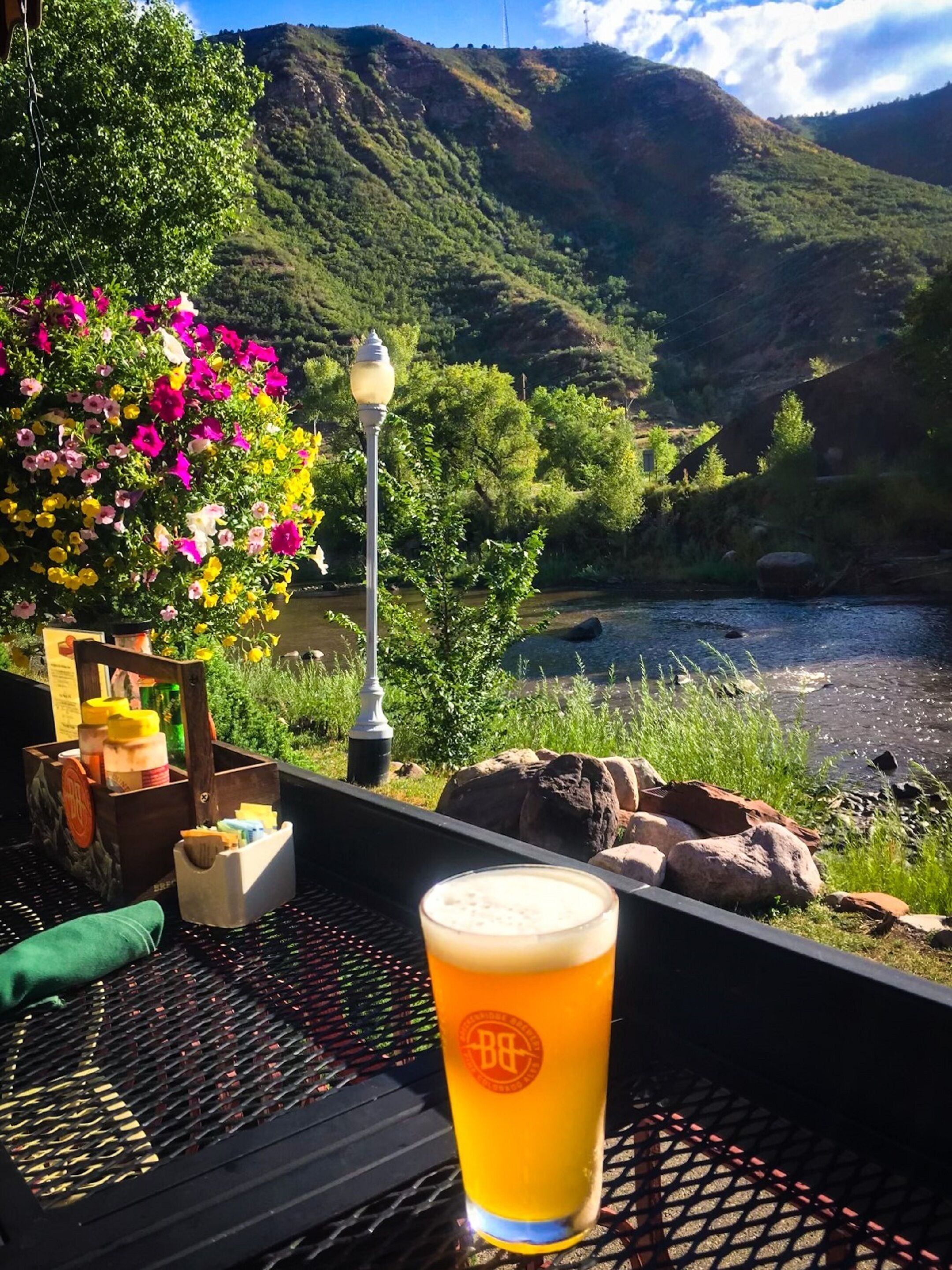 A table with a glass of beer, a wooden box, and a lamp.
