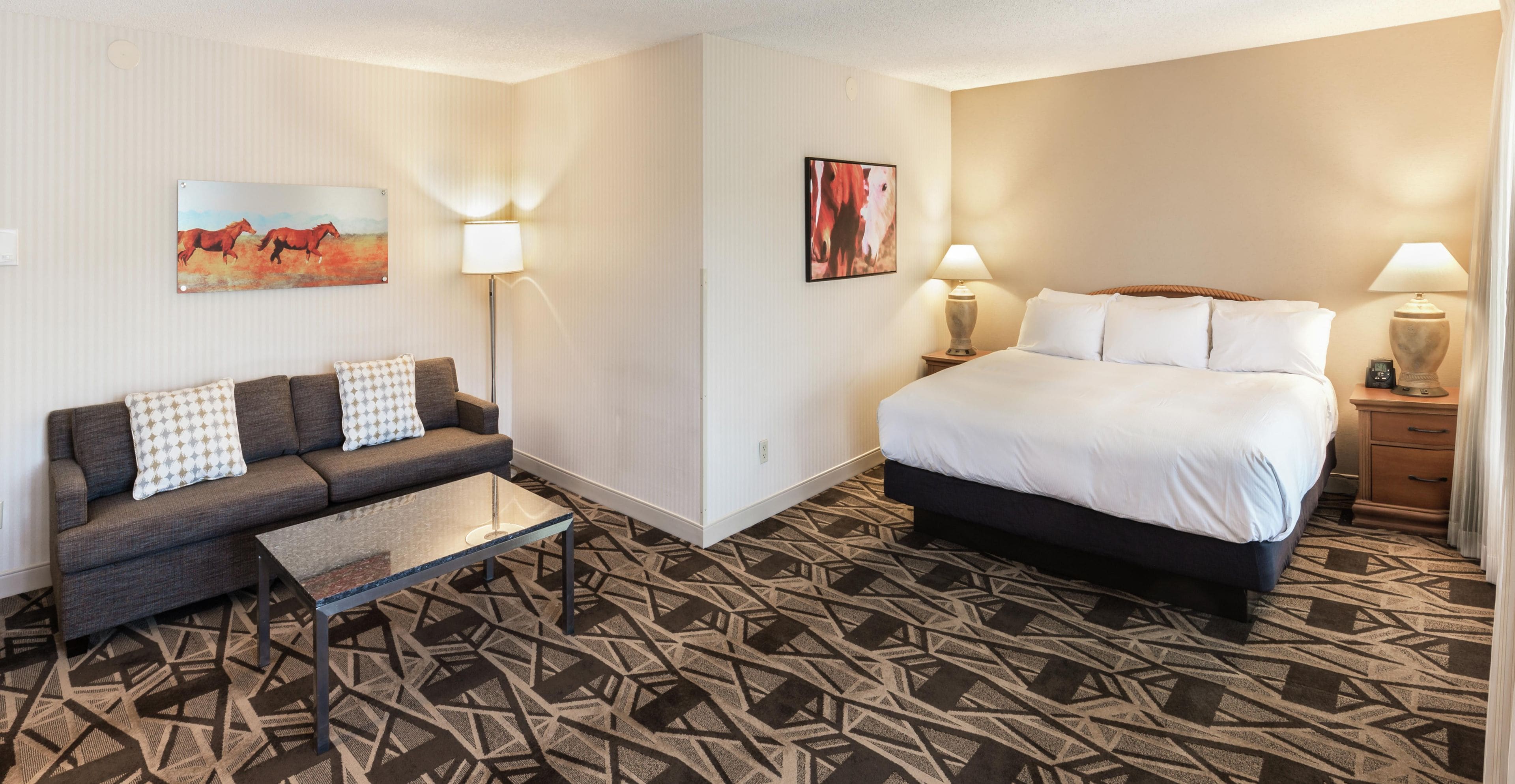 A hotel room with a bed, a sofa, a coffee table, and two wall-mounted lamps.