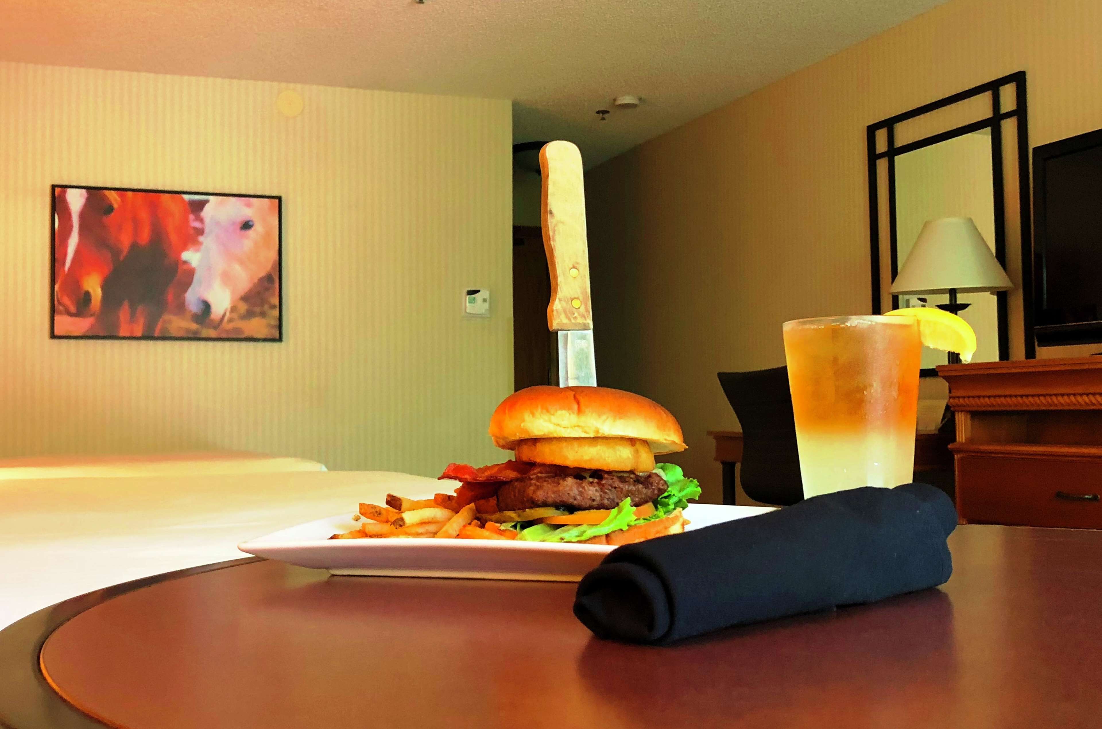 Ein Hotelzimmer mit einem Bett, einer Speisenplatte, einem Messer und einem Glas Eistee.