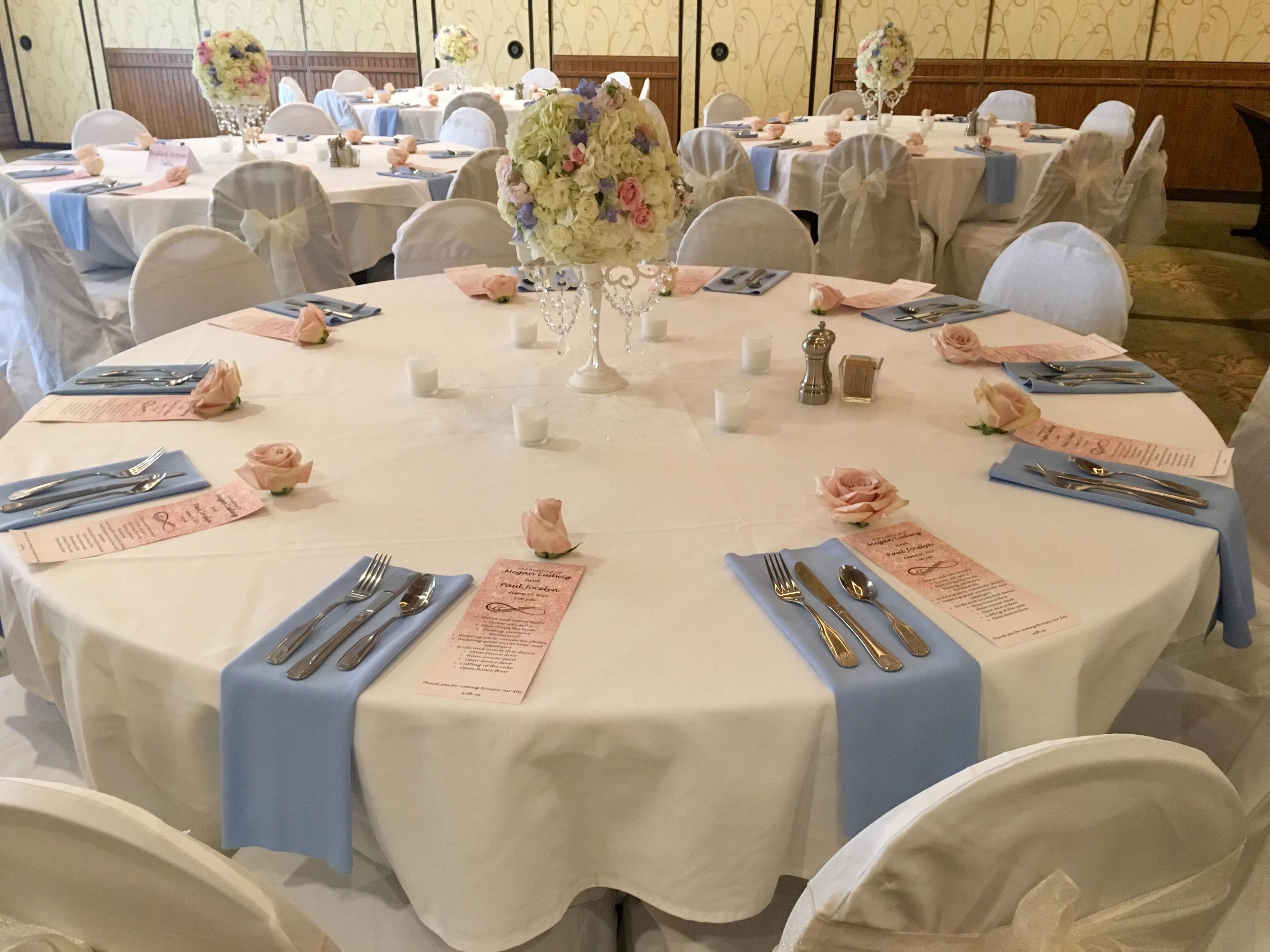 Et rundt bord dækket til en formel lejlighed med blomsterarrangementer, navneskilte og en menu.
