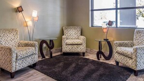 A room with three patterned armchairs, a small round table, a floor lamp, and a large window with a view. - Comfort Inn Brockville (Brockville)