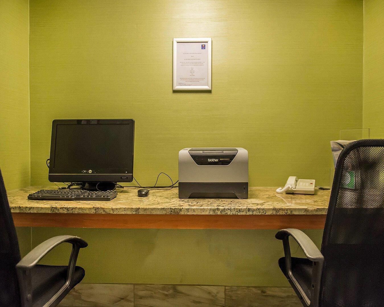 Un espacio de trabajo con un ordenador de escritorio, una impresora Brother, un teléfono y dos sillas de oficina.