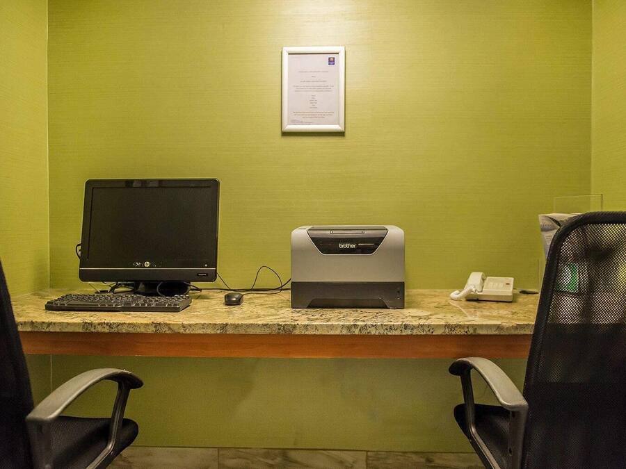 A workspace with a desktop computer, a Brother printer, a telephone, and two office chairs.
