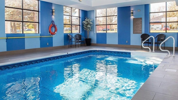 An indoor swimming pool with clear blue water, large windows, and a lifebuoy on the wall. - Comfort Inn Brockville (Brockville)