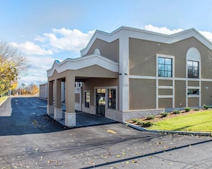 A building with a covered entrance, a large window, and a parking lot.