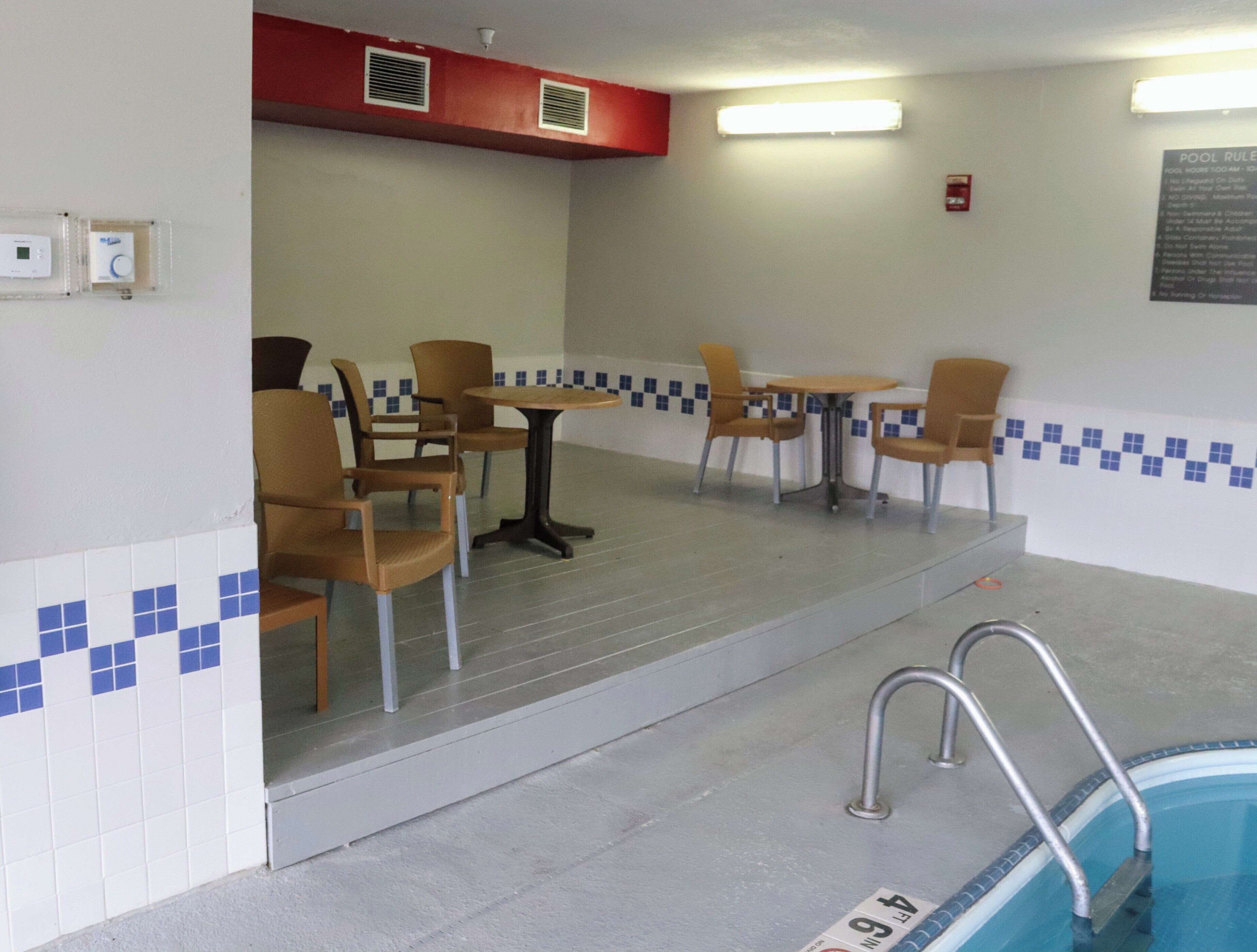 A pool area with a pool table, chairs, and a pool ladder.