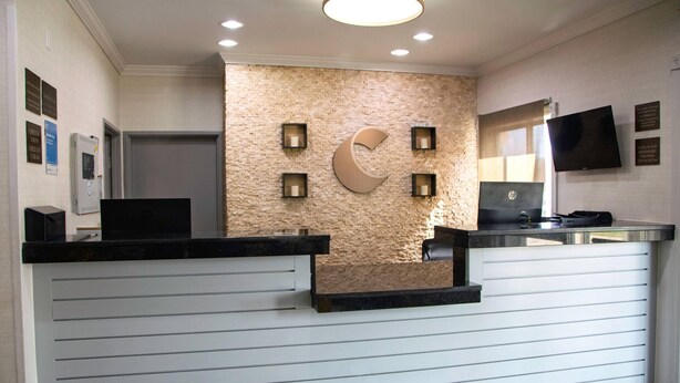 A hotel reception area with a modern design, featuring a reception desk, a wall-mounted crescent moon decoration, and a flat-screen TV. - Comfort Inn & Suites Coralville - Iowa City near Iowa River Landing (Coralville)