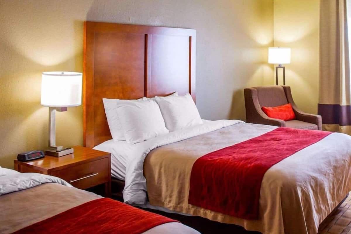 A hotel room with a large bed, a nightstand with a lamp, a chair, and a bedside table.