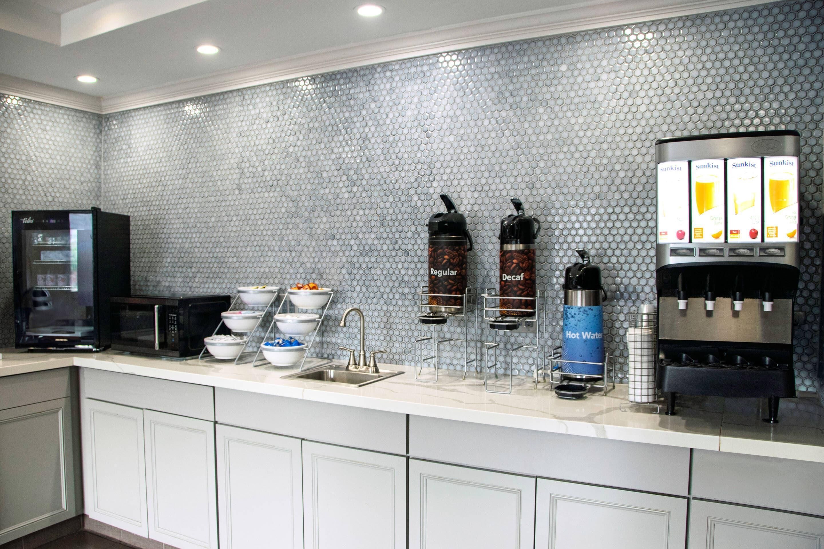Una cocina moderna con estación de café, microondas y dispensador de bebidas.