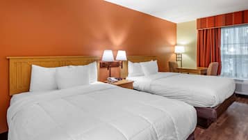 A hotel room with two beds, a desk, a chair, and a window with curtains.