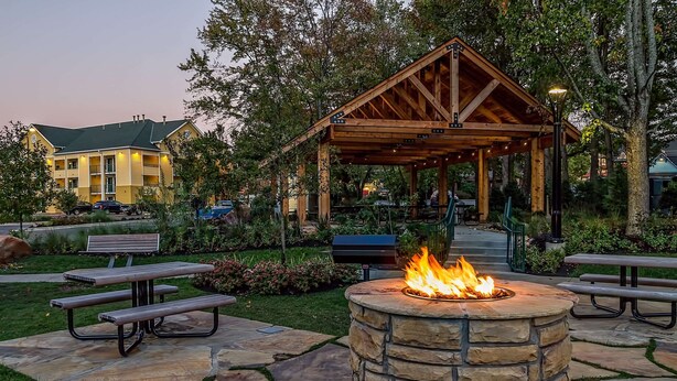 A stone fire pit with benches, a covered pavilion, and a building in the background. - Econo Lodge Pigeon Forge Riverside (Pigeon Forge)