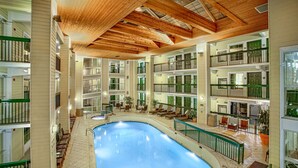 A multi-level indoor swimming pool with wooden beams, multiple balconies, and seating areas. - Econo Lodge Pigeon Forge Riverside (Pigeon Forge)