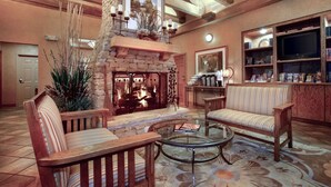 A cozy living room with a stone fireplace, wooden furniture, and a bookshelf. - Econo Lodge Pigeon Forge Riverside (Pigeon Forge)