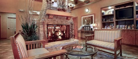 A cozy living room with a stone fireplace, wooden furniture, and a bookshelf.