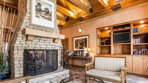 A cozy living room with a stone fireplace, wooden beams, a comfortable sofa, a coffee table, and a bookshelf. - Econo Lodge Pigeon Forge Riverside (Pigeon Forge)
