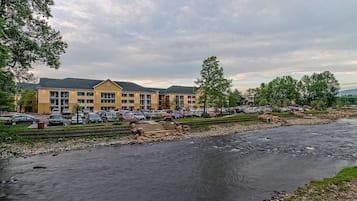 A hotel with a parking lot and a river in the foreground.