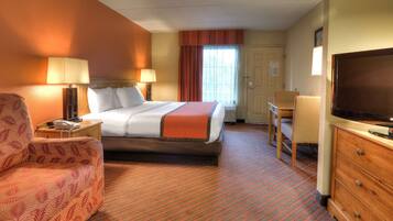 A hotel room with a bed, a desk, a chair, a television, and a dresser.