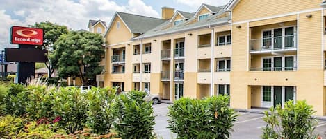 Ein mehrstöckiges EconoLodge-Gebäude mit Parkplatz und begrünten Flächen mit roten Blumen.