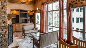 A cozy room with a stone fireplace, wooden furniture, and large windows with curtains. - Econo Lodge Pigeon Forge Riverside (Pigeon Forge)