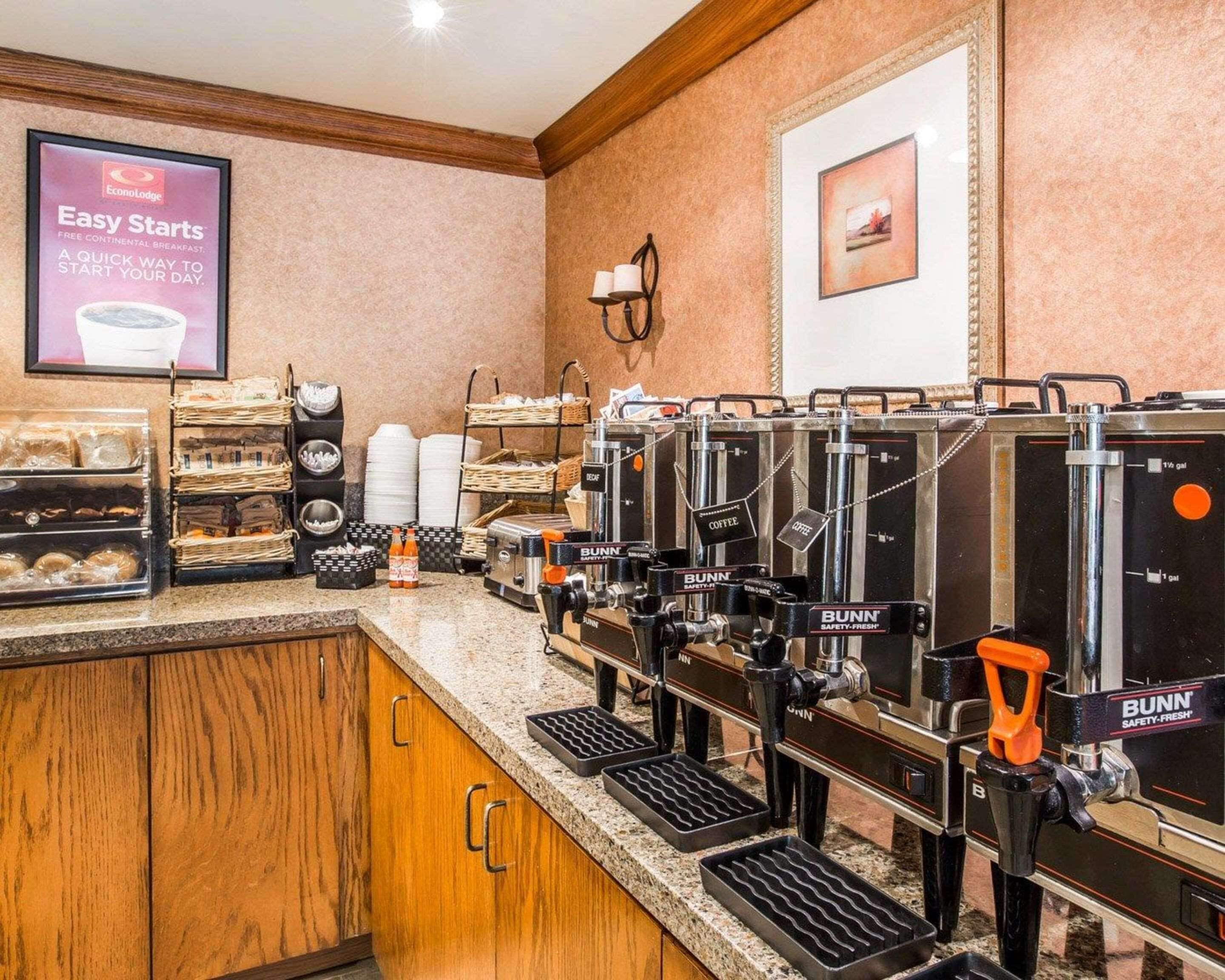 Una estación de café con varias máquinas de café, cestas de pan y un letrero que dice 'Desayuno continental Easy Starts'.