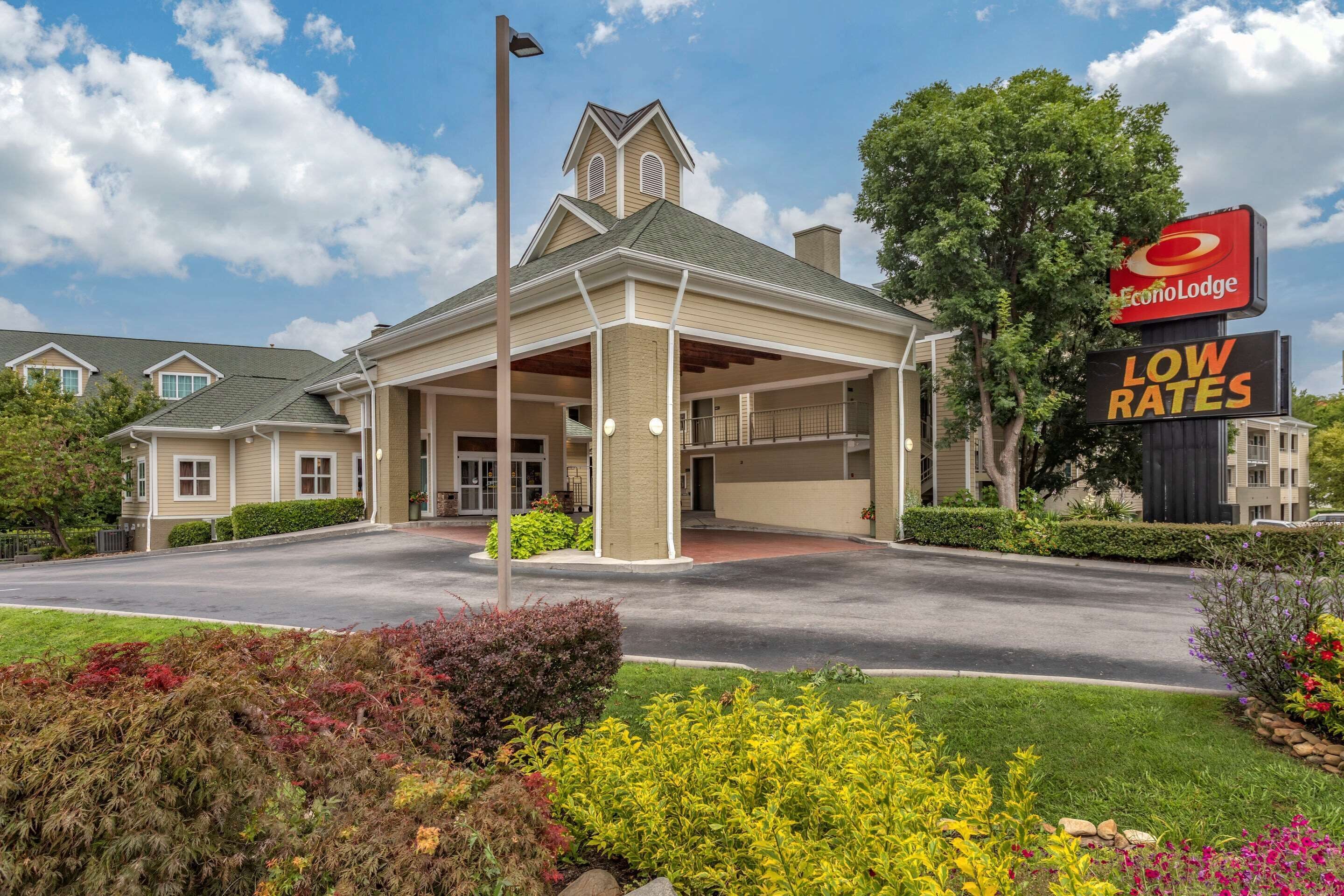 A hotel with a covered entrance, a sign advertising low rates, and a landscaped garden in front.