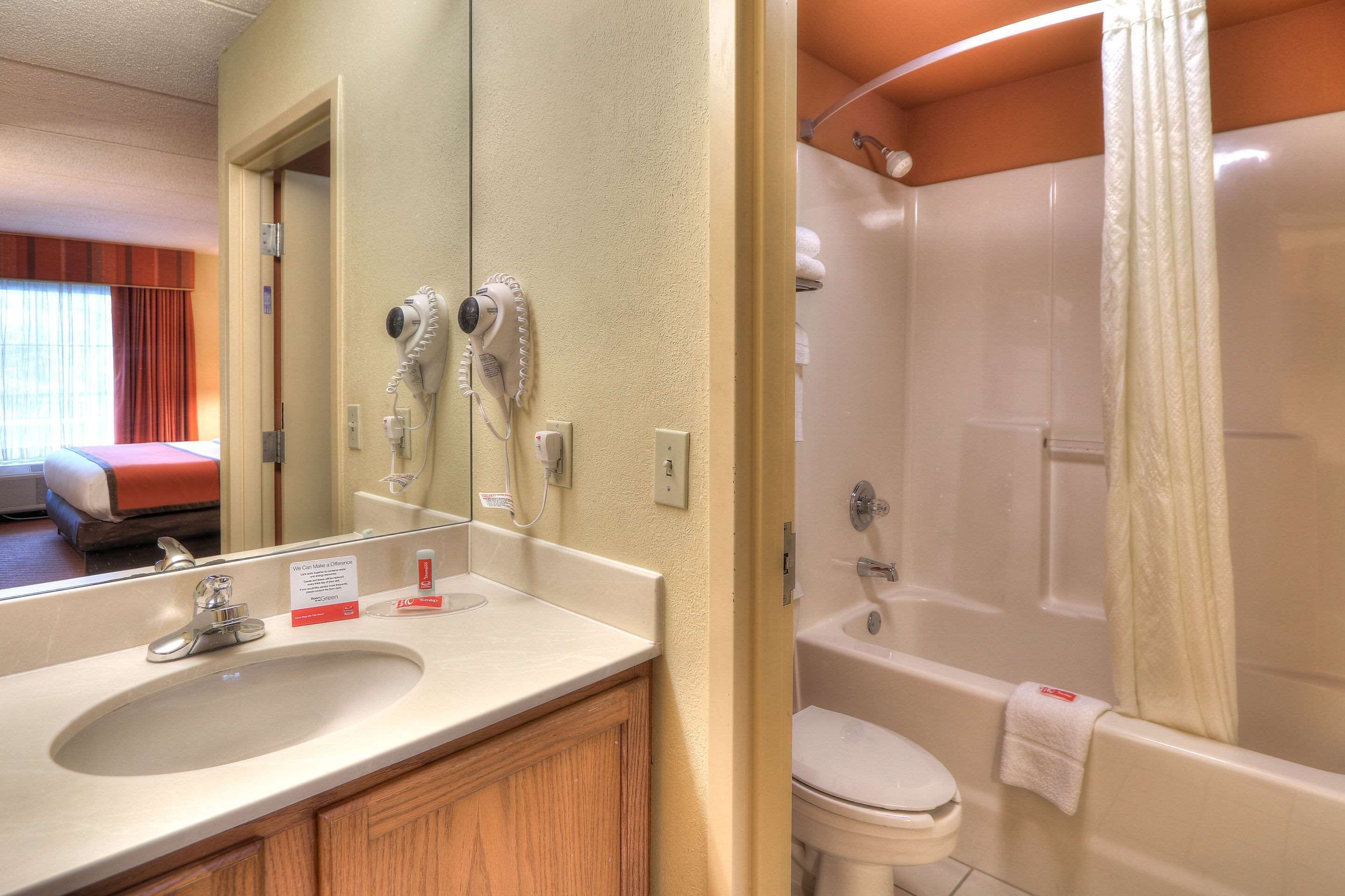 A bathroom with a sink, mirror, and a bathtub.