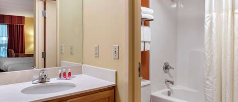 A bathroom with a sink, mirror, and bathtub.