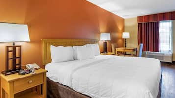 A hotel room with a large bed, wooden nightstands, a desk, and a chair.