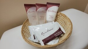A wicker basket containing three tubes of RainBreeze Conditioning Shampoo, a tube of RainBreeze Hand & Body Lotion, and a bar of RainBreeze Gentle Cleansing & Body Bar. - El Camino Inn (Daly City)