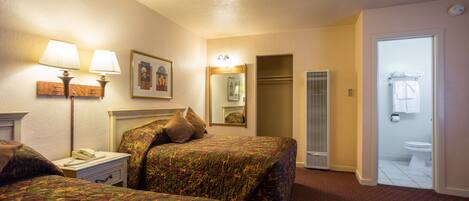 A hotel room with two beds, a nightstand with a phone, a mirror, and a bathroom visible through an open door.