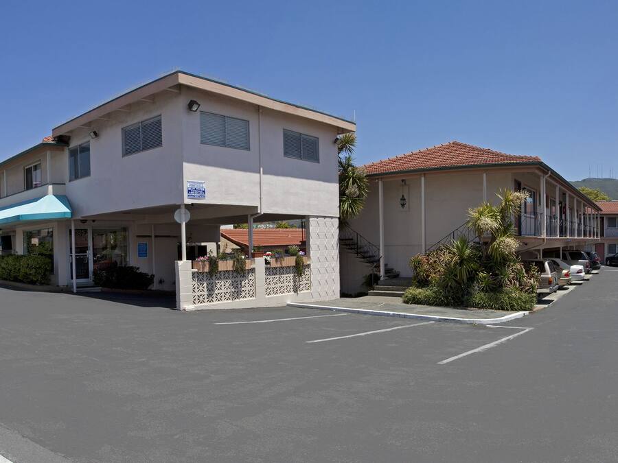 Ein Motel mit einem Schild, auf dem 'El Camino Inn' steht, und einem Parkplatz davor.