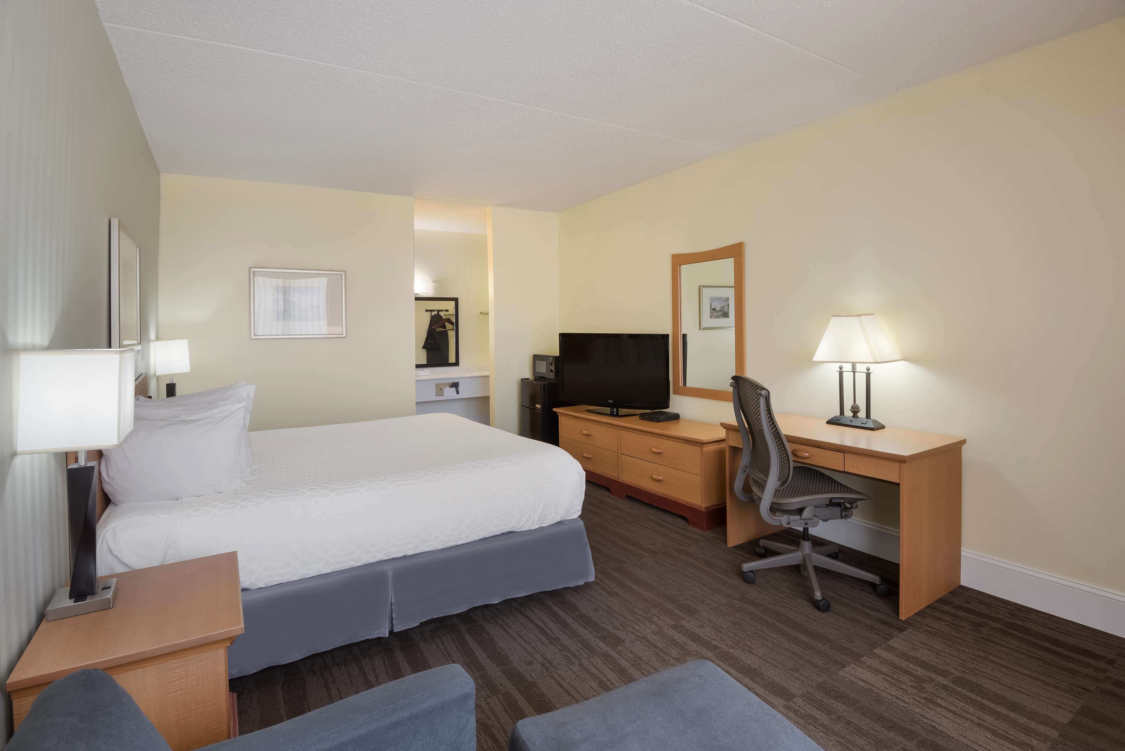 Una habitación de hotel con una cama, un escritorio, una silla, un televisor y una lámpara.