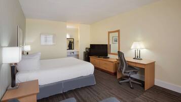 Ein Hotelzimmer mit Bett, Schreibtisch, Stuhl, Fernseher und Lampe.