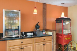 A kitchen area with a refrigerator, a popcorn machine, and a coffee maker.