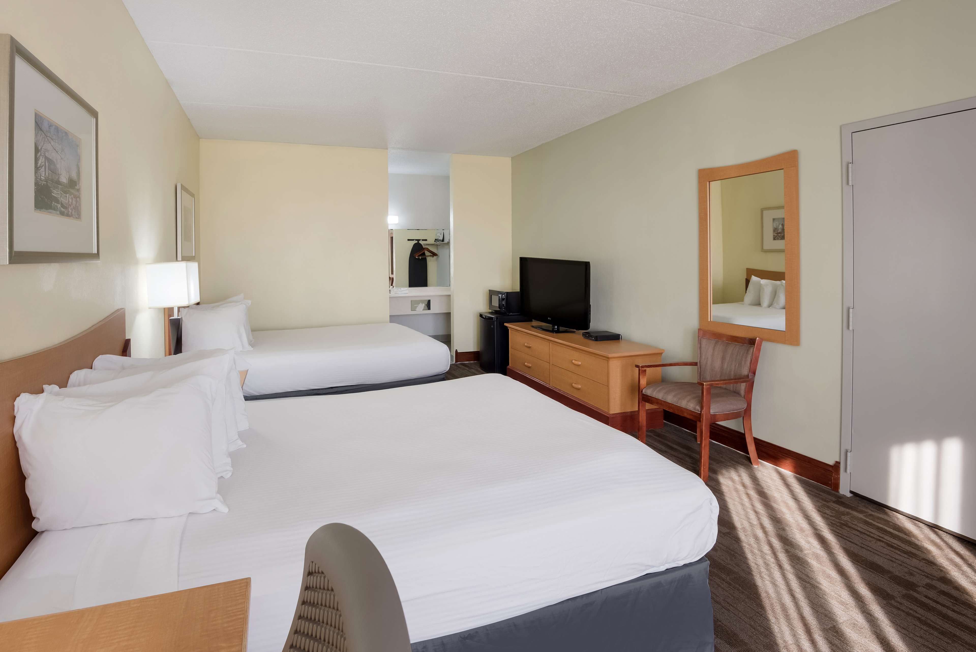 Habitación de hotel con dos camas, un escritorio, una silla, un televisor y un armario.