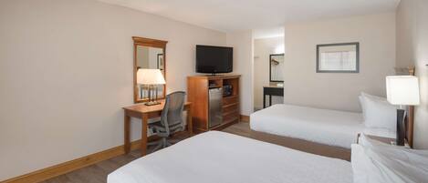 A hotel room with two single beds, a desk with a chair, a television, and a mirror.